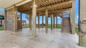 Un espacio al aire libre cubierto con vigas de madera, una escalera y vistas a la playa.