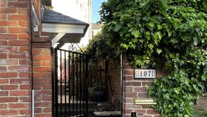 A brick building with a black gate, a bench, and a sign with the number 107.