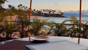 A table with a placemat, a coaster, and a candle holder with a lit candle. - MAUI BEAUTY ~ Tropical Napili Bay Lahaina 1BR King~ CONDO for 3~ Kitchen ~ AC!!! (Lahaina)