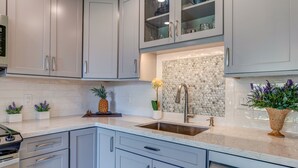 A modern kitchen with white cabinets, a granite countertop, and a stainless steel sink. - MAUI BEAUTY ~ Tropical Napili Bay Lahaina 1BR King~ CONDO for 3~ Kitchen ~ AC!!! (Lahaina)