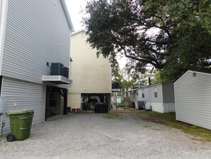 A residential area with multiple houses, a gravel driveway, and a green trash bin.