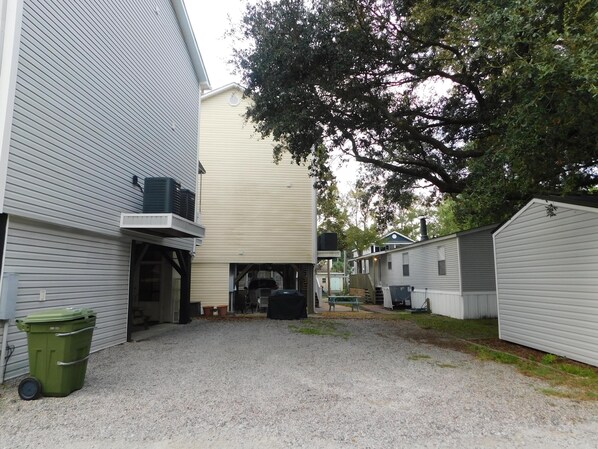 A residential area with multiple houses, a gravel driveway, and a green trash bin. - Ocean Lakes Site MH54a, 5 bdrm 3 bath sleeps 13 (Myrtle Beach)