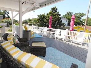 A covered outdoor seating area with wicker furniture and a white railing.