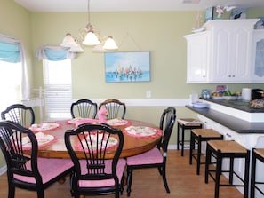 Uma área de jantar com uma mesa redonda, cadeiras pretas e um quadro na parede.