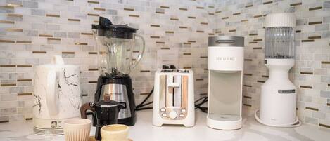 A kitchen with a coffee maker, toaster, blender, and a kettle on a countertop.