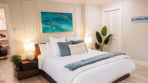 Un dormitorio con cama, lámparas de noche, mesita de noche, planta en maceta y un cuadro en la pared.