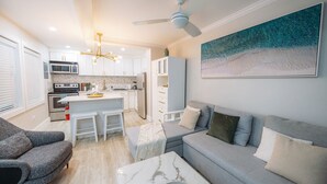 Una cocina moderna con armarios blancos, una isla central y un ventilador de techo.