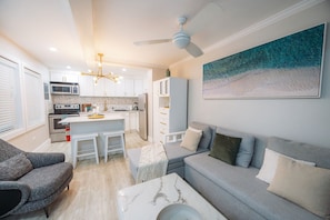 A modern kitchen with white cabinets, a central island, and a ceiling fan.