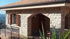 A stone building with a tiled roof, a balcony with a railing, and a view of the sea. - Villa Verde Cefalù sea view 2 (Cefalù)