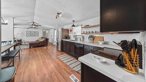 A modern kitchen with a white countertop, stainless steel appliances, and wooden shelves. - Lake Conroe 3BR | Boat Ramp, Fire Pit, Fenced Yard, Sleeps 8, Pet-Friendly (Willis)
