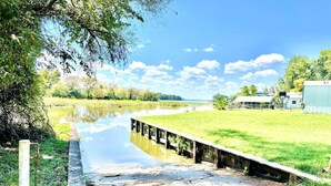 A riverside walkway with a wooden bench and a metal railing. - Lake Conroe 3BR | Boat Ramp, Fire Pit, Fenced Yard, Sleeps 8, Pet-Friendly (Willis)