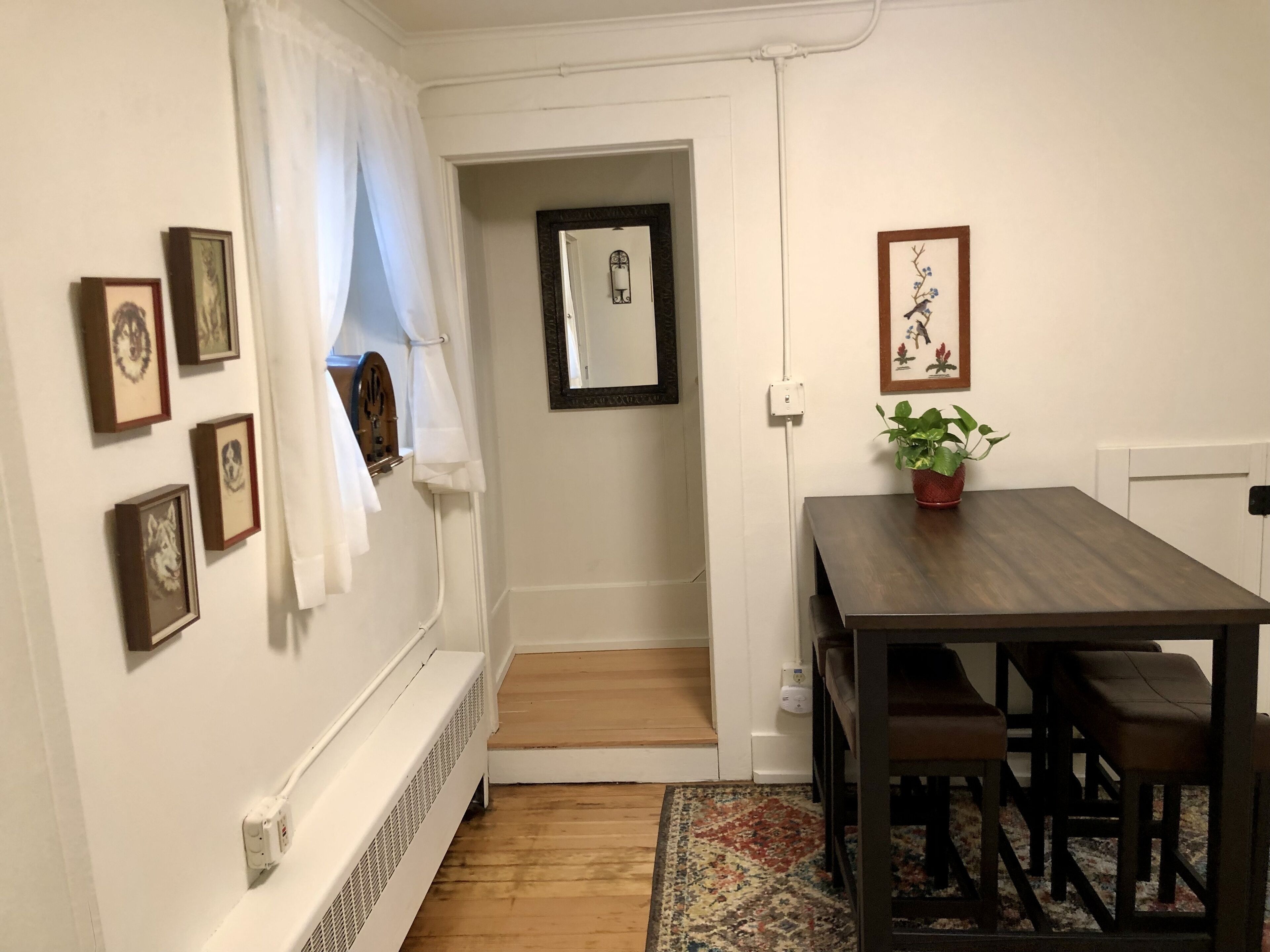 Un coin repas avec une table et des chaises en bois, une plante en pot et des tableaux encadrés au mur.