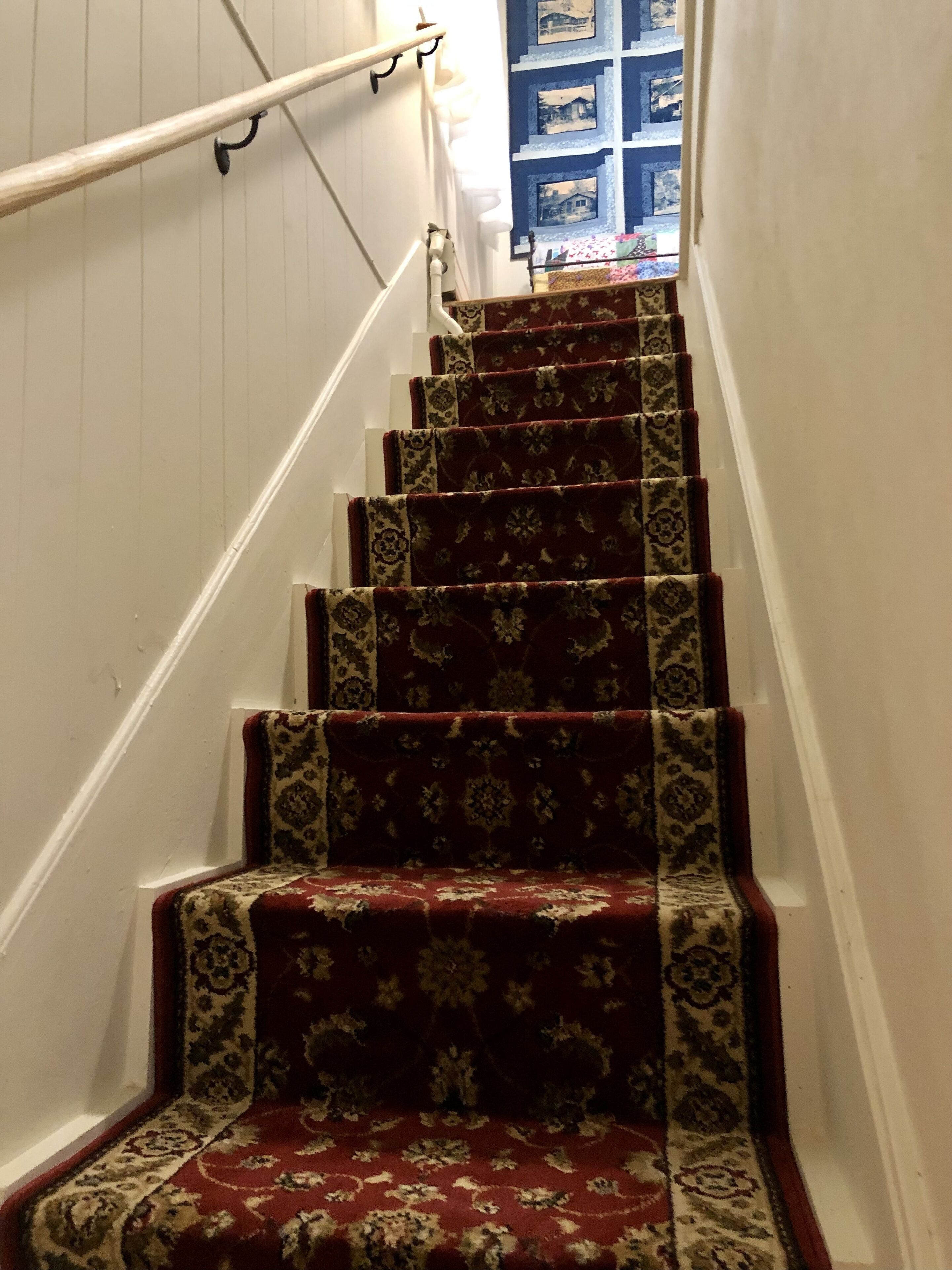 A staircase with a patterned carpet and white walls.