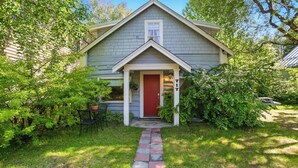 A house with a red door, a number 717, and a stone pathway leading to the entrance. - Coastal Cabin - Downtown Historical Log Home (Anchorage)