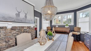 A dining area with a stone wall, a chandelier, and a painting of deer. - Historic, Recently Renovated Home Near Savannah River & Downtown Augusta! (Augusta)