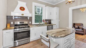 A modern kitchen with white cabinetry, stainless steel appliances, a marble island, and pendant lighting. - Historic, Recently Renovated Home Near Savannah River & Downtown Augusta! (Augusta)