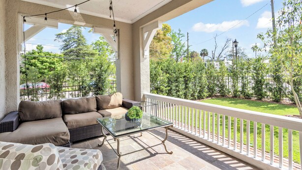 A covered patio with a glass table, a sofa, and a view of a green lawn and trees. - Historic, Recently Renovated Home Near Savannah River & Downtown Augusta! (Augusta)