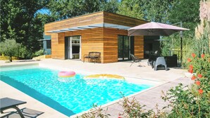 Una casa moderna con fachada de madera, piscina y mobiliario de exterior.