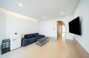 A modern living room with a sofa, coffee table, and a flat-screen TV mounted on the wall.