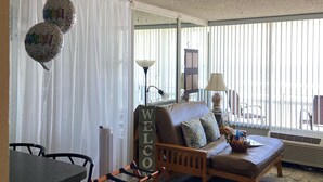 A living room with a sofa, a small table, and a chair. There are balloons with the word "Celebrate!" on them.