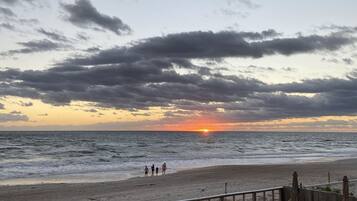 Ein Poolbereich mit Blick auf Strand und Meer bei Sonnenuntergang.
