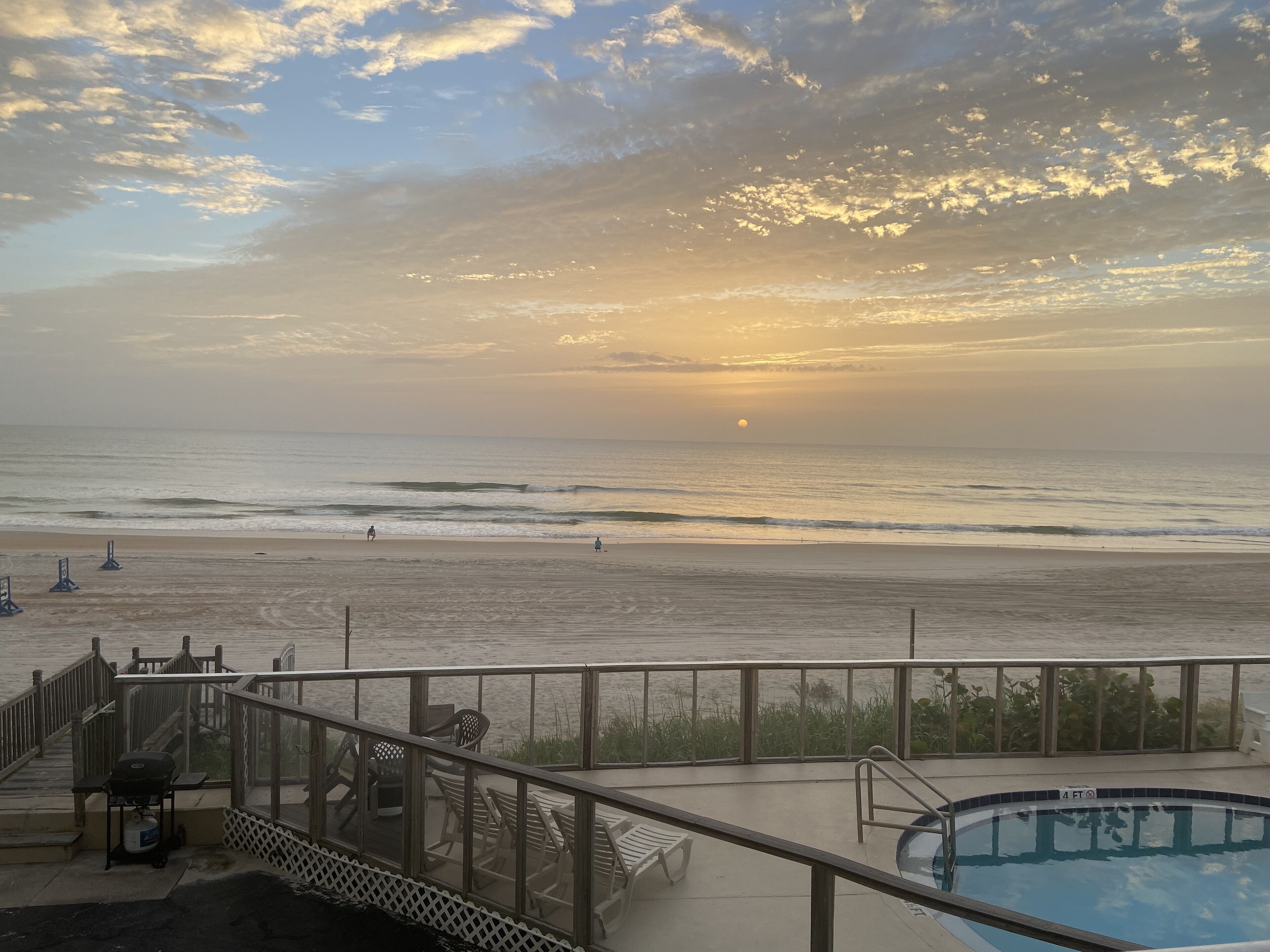A beach view with a pool and deck chairs.