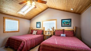 A bedroom with two beds, wooden ceiling beams, and a skylight. - Stay in a historical mountain town! (Pitkin)