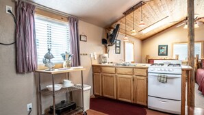A compact kitchen with wooden cabinets, a white stove, and a small countertop. - Stay in a historical mountain town! (Pitkin)