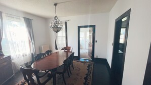 Un comedor con una mesa y sillas de madera, una araña y una alfombra estampada.