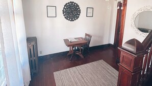 Un comedor con mesa y sillas de madera, una araña y un espejo decorativo.