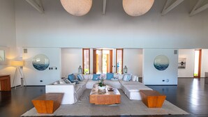 Amplia sala de estar con un sofá modular grande, una mesa de centro de madera y dos espejos grandes colgados en la pared.