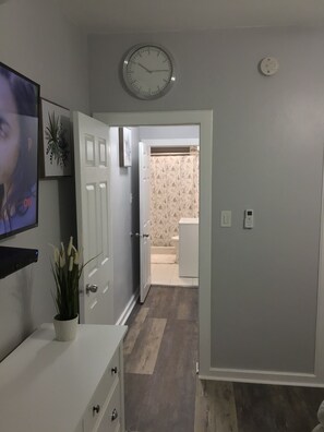 Enter a well-appointed hallway leading to a bathroom with a television and a digital clock.