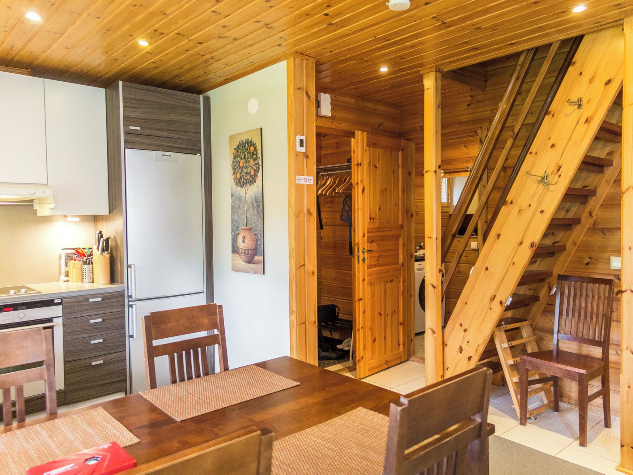 A wooden interior with a kitchen, dining area, and a staircase.