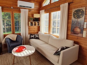 A cozy room with a sofa, a chair, a small table, and a painting on the wall.