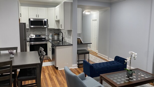 A modern kitchen with white cabinets, stainless steel appliances, and a dark countertop. - Remodeled Spacious Apartment in Perfect Location (Boston)