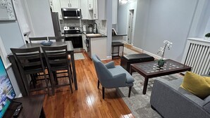 A modern apartment with a dining area, kitchen, and living room. - Remodeled Spacious Apartment in Perfect Location (Boston)