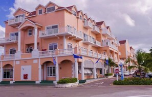 A multi-story hotel with balconies, a red mailbox, and palm trees in the background. - Lagoon Luxury at Sandyport (Nassau)