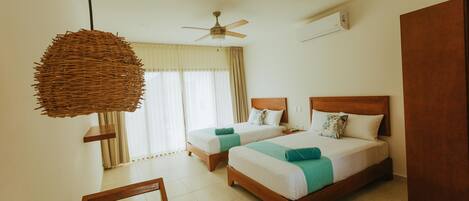 A hotel room with two beds, a ceiling fan, an air conditioning unit, and a large woven light fixture.