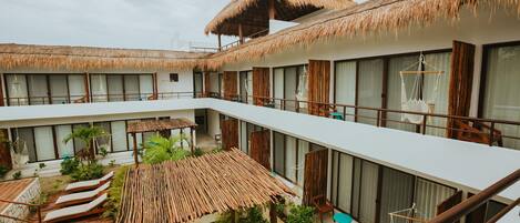 Un resort con varios balcones, techos de paja y una zona de piscina.
