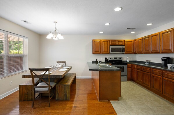 A modern kitchen with wooden cabinets, a central island, and a dining area with a bench.