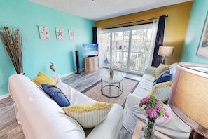 A living room with a sofa set, a coffee table, and a television. - Steps from St. Armands! Walk to Beach, Heated Pool (Sarasota)