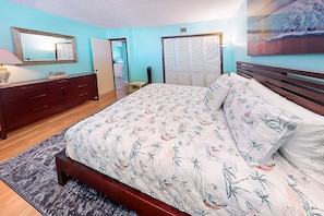 A bedroom with a bed, a dresser, a mirror, and a closet.