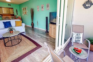 Una sala de estar con un sofá, una mesa de centro, un televisor y un comedor con una mesa y sillas.