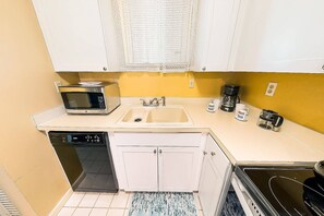 A compact kitchen with a microwave, sink, coffee maker, and dishwasher.