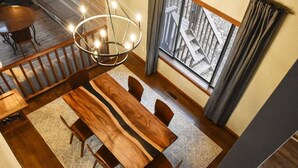 Ein Essbereich mit Holztisch und -stühlen, einer Chandelierleuchtre und Blick auf eine Holzterrasse.