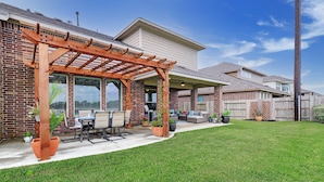 A residential backyard with a wooden pergola, patio furniture, and potted plants. - Elegant spacious home with water view. Prime location- Richmond, Katy, Houston, Rosenberg. (Richmond)