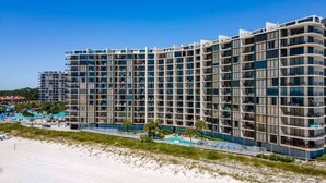 A modern hotel with multiple floors, large windows, and a pool area.