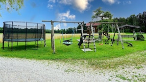 A playground with a trampoline, swing set, and climbing structure. - Vacation apartment Schwalbennest (Chieming)