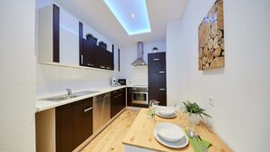 Une cuisine moderne avec une table en bois mise pour le repas, un four à micro-ondes, un four traditionnel et un évier.