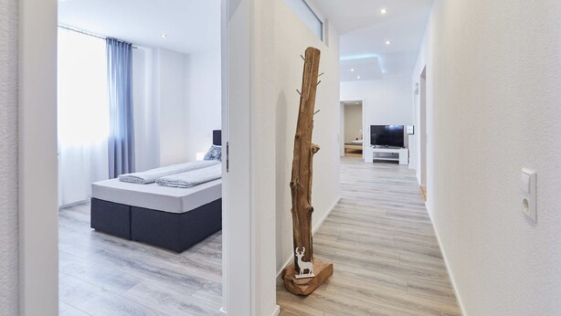 Une chambre à coucher moderne avec un lit, une sculpture en bois et un téléviseur en arrière-plan.